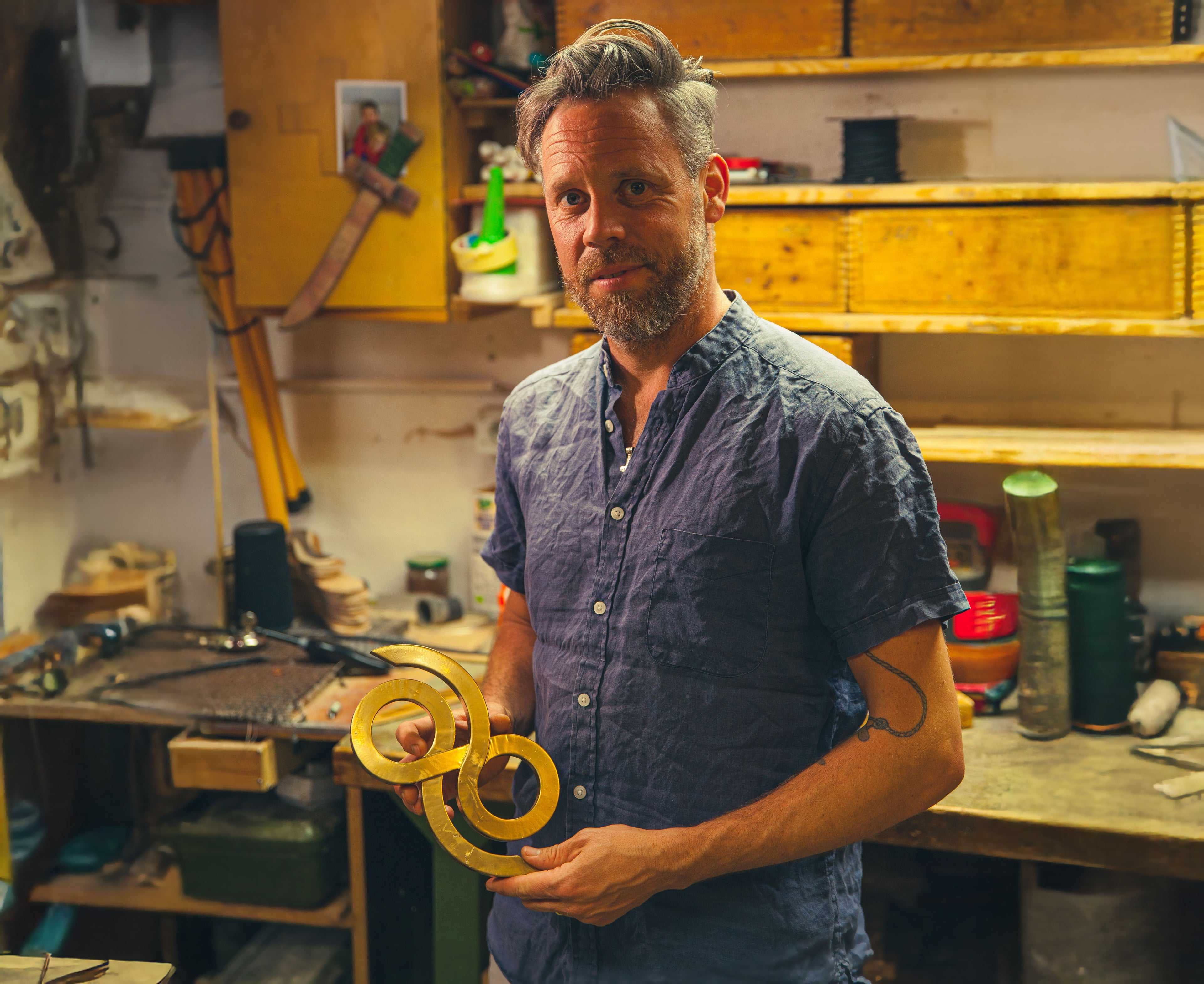 Man holding a yellow object in a workshop setting