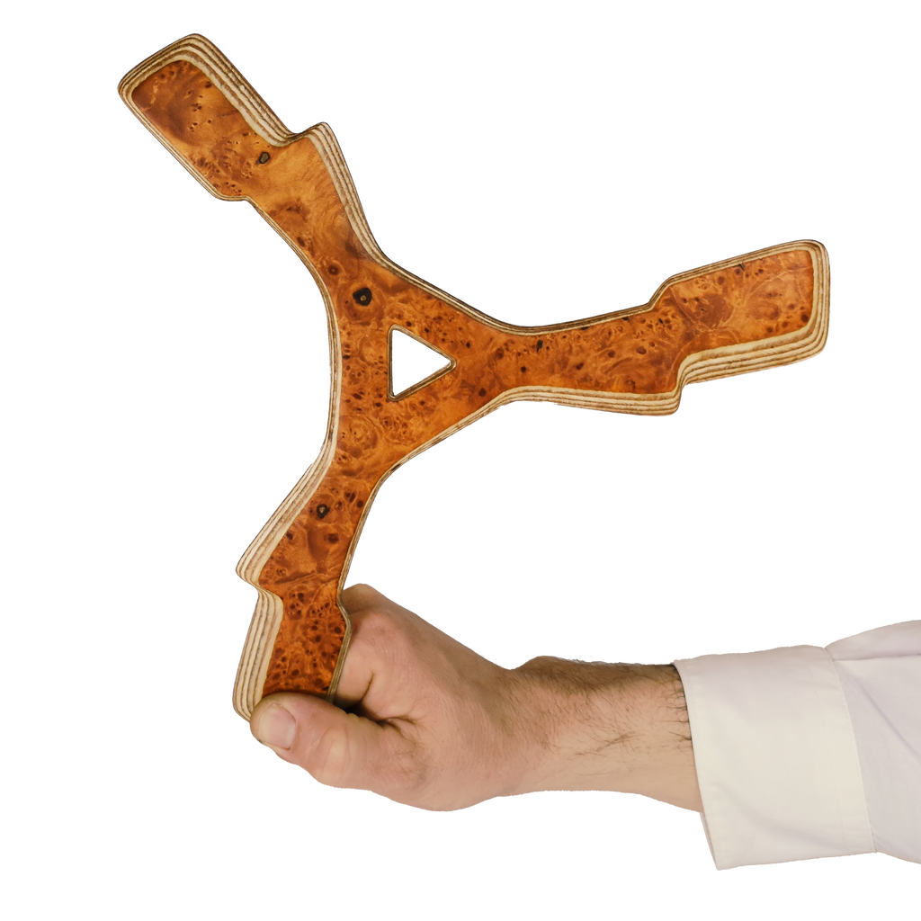 Image of Zeus Boomerang size comparison Hand holding Y-shaped Karelian birch burl boomerang showing rich amber wood patterns and plywood edges